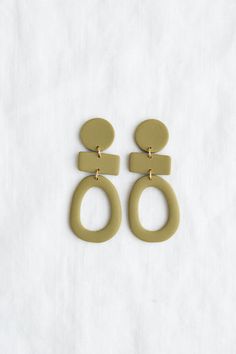 two pairs of earrings on a white surface with one earring in the shape of an oatmeal