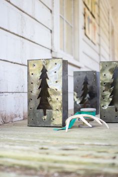 three metal boxes with trees on them sitting in front of a building