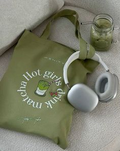 a green bag sitting on top of a couch next to a pair of headphones