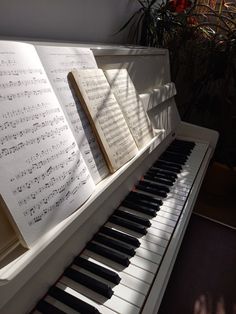 an open book is sitting on top of a piano keyboard with sheet music resting on it