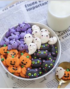 a bowl filled with halloween treats next to a glass of milk