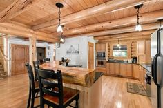 a kitchen and dining room with wood floors in a log cabin style home on the shores of lake michigan