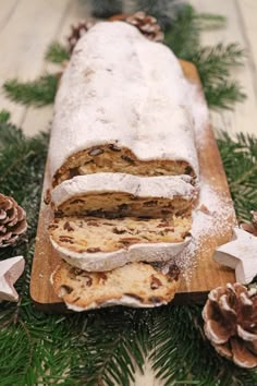 a loaf of bread sitting on top of a wooden cutting board next to pine cones