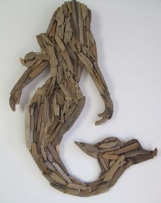 a sculpture made out of driftwood sitting on top of a white table next to a wall