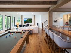 a pool table in the middle of a living room with lots of furniture and windows