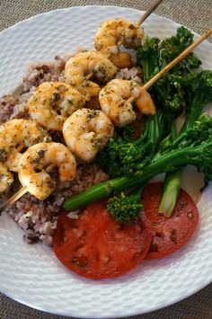 shrimp, broccoli and rice with tomatoes on a white plate next to chopsticks