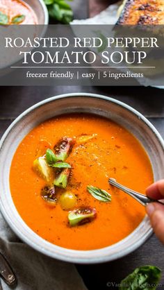 roasted red pepper tomato soup in a white bowl with a spoon and garnish