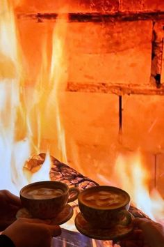 two cups of hot chocolate in front of a fire