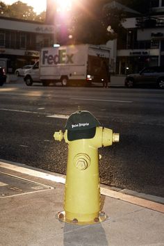 a yellow fire hydrant sitting on the side of a road next to a street