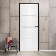 an empty chair sitting in front of a white door with black frame on the wall