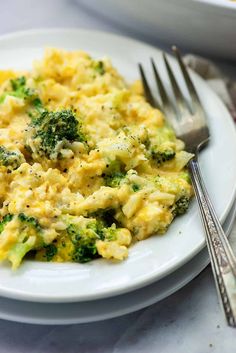 a white plate topped with eggs and broccoli on top of a table next to silverware