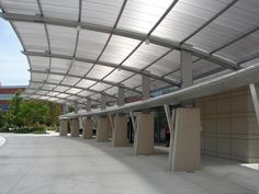 an empty parking lot with concrete pillars and metal roof overhanging the entrance to a building