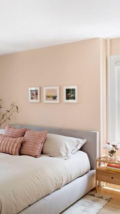 a white bed sitting next to a window with pictures on the wall above it in a bedroom