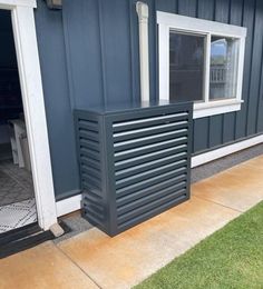 an air conditioner sitting outside of a house on the side of a building with grass in front of it