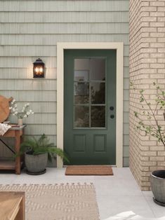 a front door with a bench and potted plants on the porch next to it