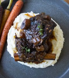 a plate with mashed potatoes, carrots and beef on it next to some vegetables