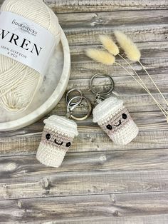 two crocheted keychains with faces on them next to a ball of yarn