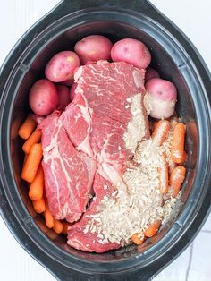 meat, potatoes and carrots in a crock pot on a white tablecloth