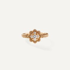 a gold ring with a diamond in the middle and an open flower design on top