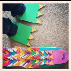 a person standing next to a colorful skateboard on the floor with paper cut outs