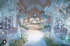 an elaborately decorated wedding venue with white flowers and trees in the center, surrounded by snow