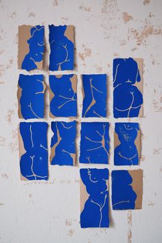 several pieces of blue paper cut into squares on a white wall with torn up edges