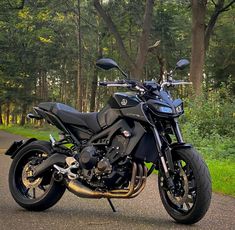 the motorcycle is parked on the side of the road in the woods near some trees