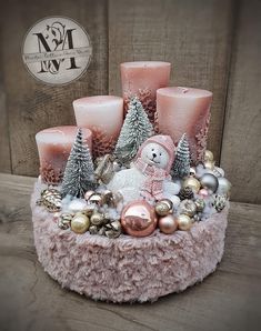 a pink christmas centerpiece with candles, ornaments and a teddy bear on it's side