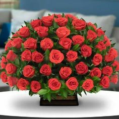 a bouquet of red roses on a table in front of a living room couches