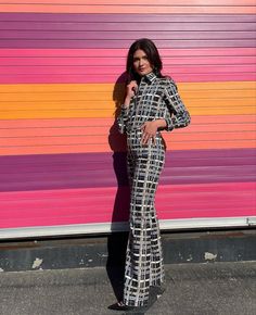 a woman standing in front of a colorful wall with her hands on her hips and looking at the camera