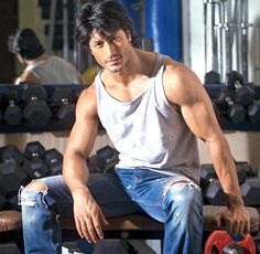 a man sitting on top of a bench next to a rack of dumbbells