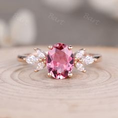 a pink diamond ring with three white diamonds on the bottom and an oval cut in the middle