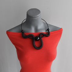 a mannequin with a red top and black necklace on it's neck