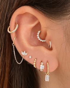 a close up of a person wearing ear piercings with chains and stones on them