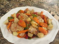 a white plate topped with chicken and veggies next to a granite counter top