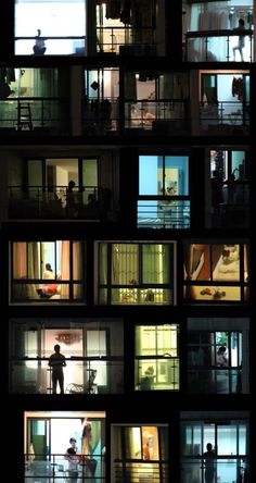 multiple shots of people standing in the windows of a building at night, all lit up