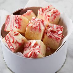 a white container filled with red and white swirled cake squares on top of a marble counter