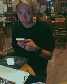 a young man sitting at a table looking at his cell phone