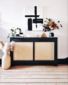 a black and white cabinet with some plants on top of it in a living room