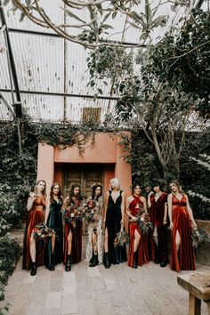 a group of women standing next to each other in front of a building with greenery