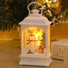 a white lantern sitting on top of a table next to a christmas tree and presents