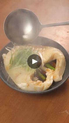 a spoon scooping some food out of a bowl on top of a wooden table