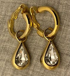 These vintage Kenneth Jay Lane earrings are in outstanding condition, and are signed KENNETH LANE on the back of each clip. The clear faceted teardrop headlight crystal is suspended in a center frame, leaving the front and back open to capture light.   These crystal drops dangle from the top hoop with clip.   Versatile earrings; The hoops can be worn alone whenever desired by sliding the bail off of the hoop.    Overall: 1.5" long from top of hoop to bottom of crystal drop. Drop alone: 1" long f Crystal Drop, Kenneth Jay Lane, Earrings Vintage, Designer Jewelry, Bridal Earrings, Clip On Earrings, Gold Tones, Fashion Jewelry, Vintage Fashion