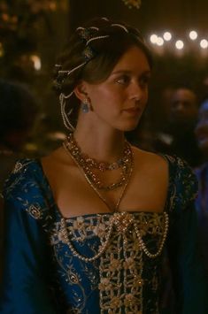 a woman in a blue dress with gold jewelry on her neck and headpieces