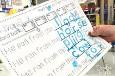 a person holding up a piece of paper with writing on it in front of a classroom