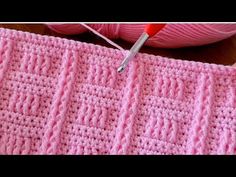 a pink crochet piece with a needle in it