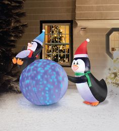 two inflatable penguins are standing next to each other on the snow covered ground