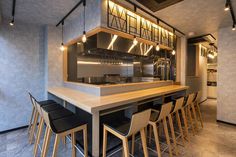 an empty bar with stools and lights on the ceiling above it is lit up by recessed lighting