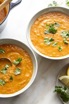 two bowls of soup with cilantro and lime on the side