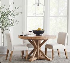 a dining room table with four chairs and a bowl of fruit on the table next to it